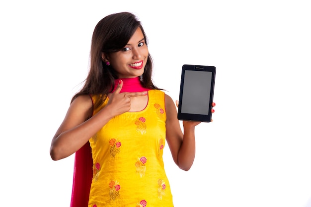 Young beautiful girl showing a blank screen of a smartphone or mobile or tablet phone on a white background