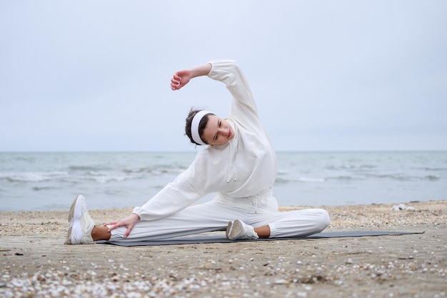 The young beautiful girl sitting on the yoga mat and doing exercises High quality photo