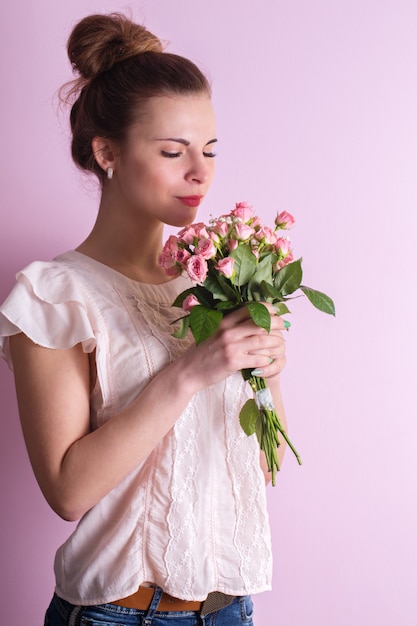 Young beautiful girl sniffing a bouquet of pink roses on valentine's day