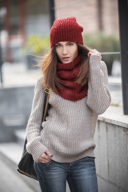 young beautiful girl student in a knitted sweater red scarf and hat and a backpack