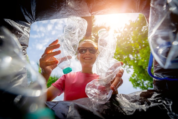 A young beautiful girl throws sorted garbage into special bins