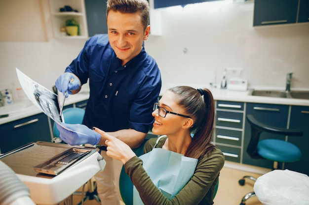 A young and beautiful girl treats her teeth with a dentist