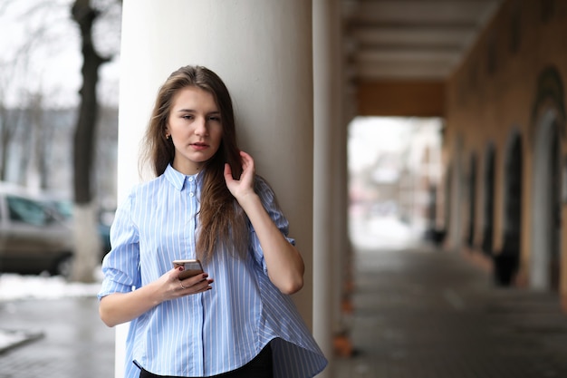 Young beautiful girl on a walk near a building with a column