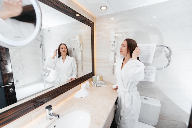 A young beautiful girl washes her face and holds a towel in a beautiful white bathroom A fresh good morning at the hotel Rest and travel Hotel recreation and tourism