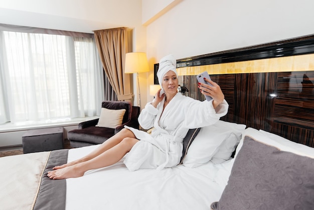 A young beautiful girl in a white coat is talking on the phone in her hotel room Rest and travel Hotel recreation and tourism