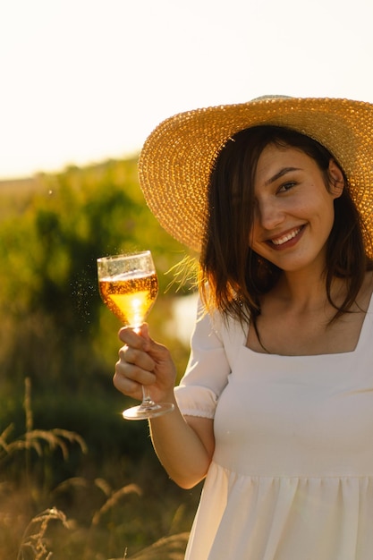 Young beautiful girl in a white dress having a picnic with a glass of champagne or white wine