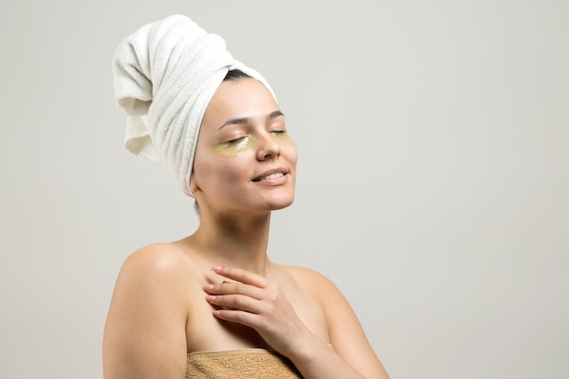 Young beautiful girl in a white towel on his head wears collagen gel patches under her eyes Mask under eyes treatment face