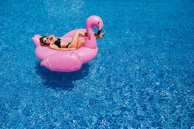 A young beautiful girl with a beautiful figure in a black swimsuit and sunglasses