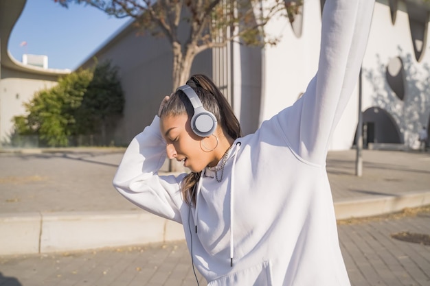 Young beautiful girl with headphones happy smiling and dancing in the street