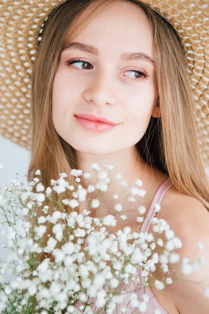 Young beautiful girl with long hair and hat posing with a bouquet of white flowers. Toning.