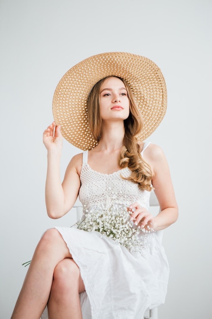 Young beautiful girl with long hair and hat posing with a bouquet of white flowers. Toning.