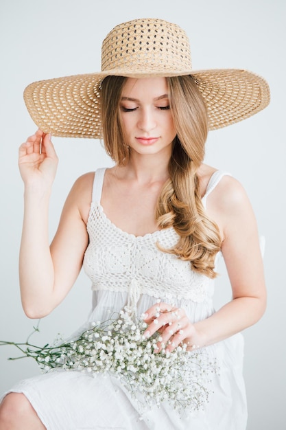 Young beautiful girl with long hair and hat posing with a bouquet of white flowers. Toning.