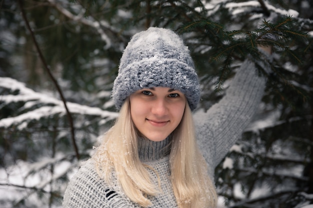 Young beautiful girl with long white hair plays snowballs. She has fun, throws snow and rejoices the snowfall. Winter walk outside.