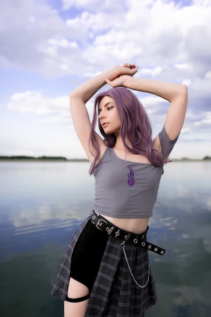 Young beautiful girl with purple hair on a background of clouds