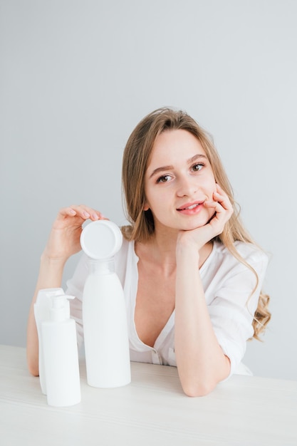 Young beautiful girl with white cosmetic bottles of different sizes. The concept of zero waste. Toning.