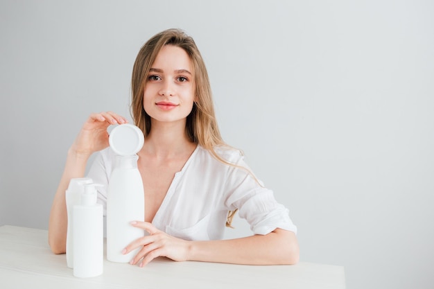 Young beautiful girl with white cosmetic bottles of different sizes. The concept of zero waste. Toning.