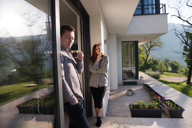 young beautiful handsome couple enjoying morning coffee on the door of their luxury home villa