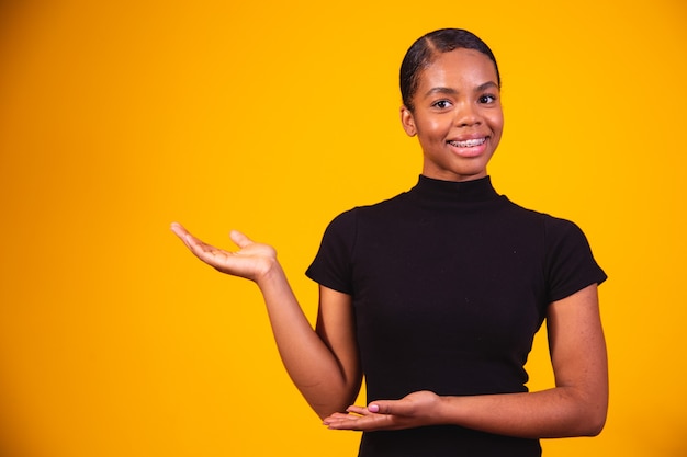 Young beautiful happy afro woman pointing to the side indicating space for text.