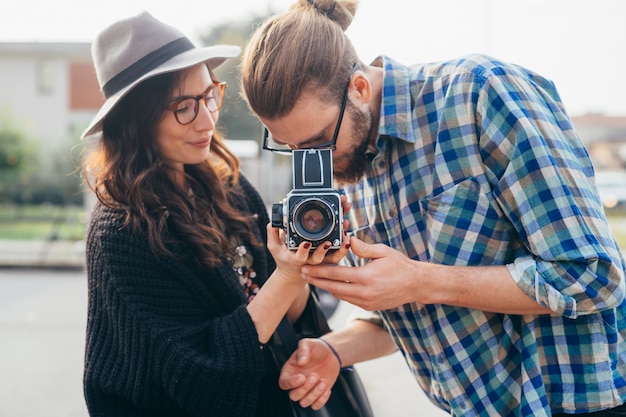 Young beautiful happy couple outdoor using old camera