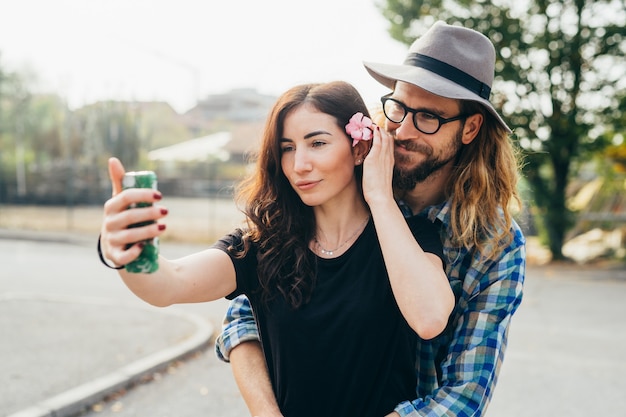 Young beautiful happy couple walking outdoor taking selfie using smartphone