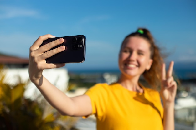 Young beautiful happy woman blogger is taking selfie picture of herself on frontal camera to social