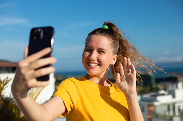 Young beautiful happy woman blogger is taking selfie picture of herself on frontal camera to social