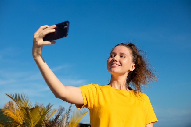 Young beautiful happy woman blogger is taking selfie picture of herself on frontal camera to social