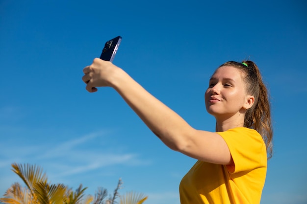 Young beautiful happy woman blogger is taking selfie picture of herself on frontal camera to social