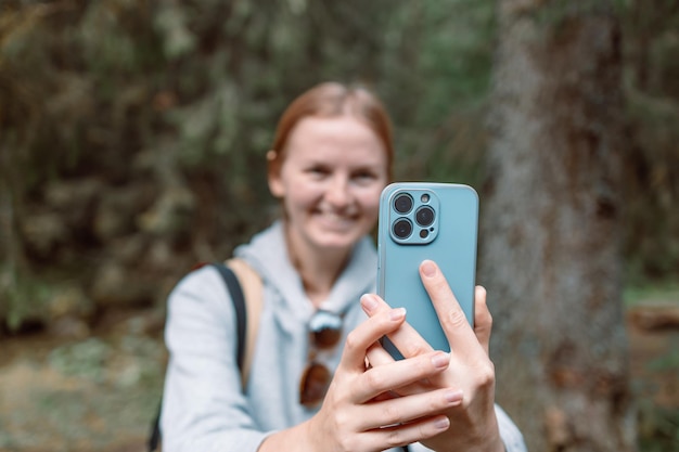 Young beautiful hiker woman taking selfie portrait on the top of mountainHappy smiling girl using her smartphone