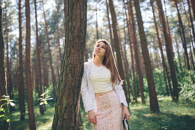 Young beautiful hippie woman walks in the summer forest laughs dances and enjoys life and nature