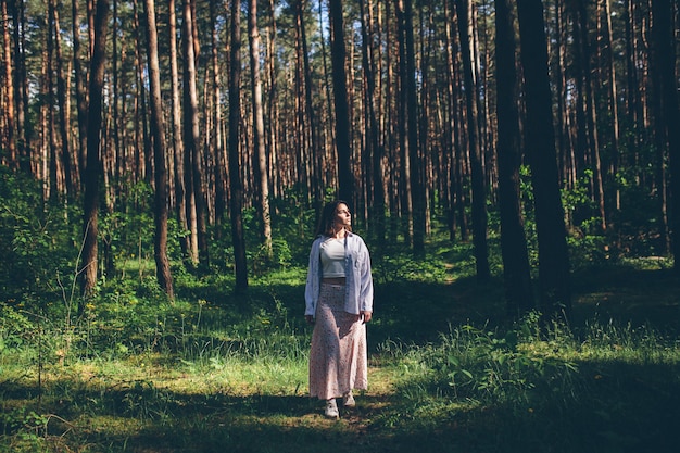 Young beautiful hippie woman walks in the summer forest laughs dances and enjoys life and nature