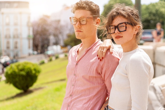 Young beautiful hipster couple in sunglasses in love walking on old city street