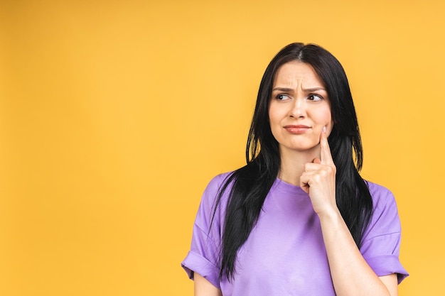 Young beautiful hispanic sad woman serious and concerned looking worried and thoughtful facial expression feeling depressed isolated over yellow background in sadness and sorrow emotion