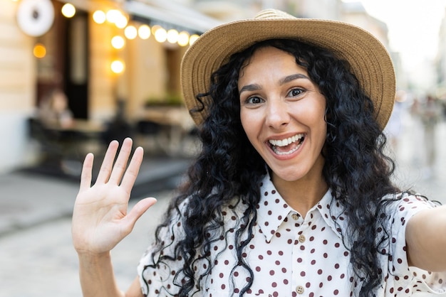 Young beautiful hispanic woman smiling and looking into phone camera traveler uses smartphone app