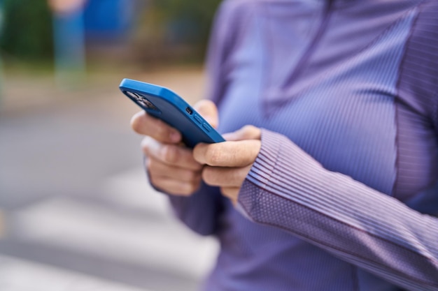 Young beautiful hispanic woman wearing sportswear using smartphone at street