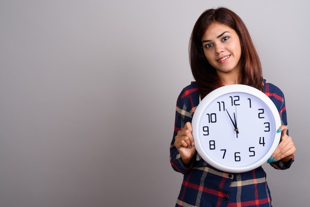 Young beautiful Indian woman wearing checked shirt against gray