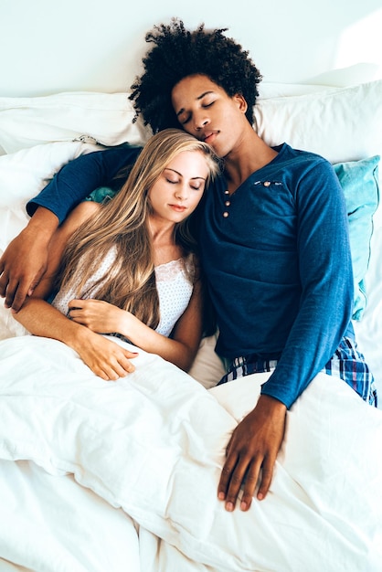 Young beautiful interracial couple in bed sleeping