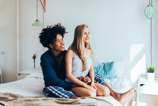 Young beautiful interracial couple relaxed sitting in bed cuddling