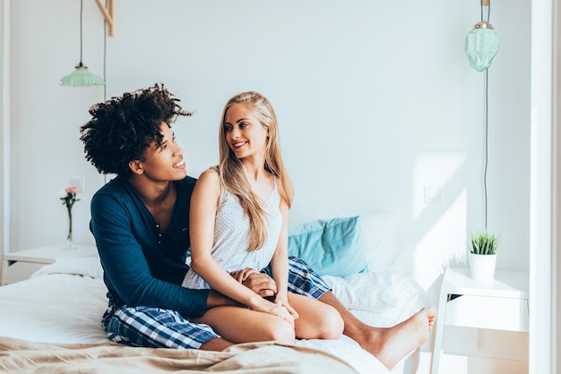 Young beautiful interracial couple relaxed sitting in bed cuddling