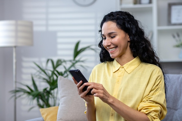 Young beautiful latin american woman using phone alone at home woman smiling and happy sitting on