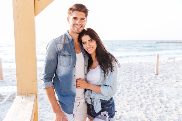 Young beautiful laughing couple looking at each other standing at the beach