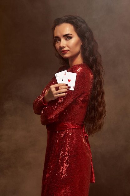 Photo young beautiful lucky brunette in a red evening dress shows her cards a pair of aces