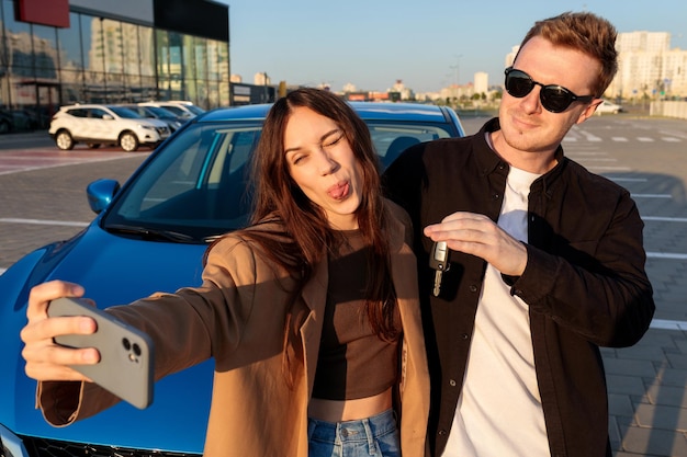 A young beautiful married couple takes a selfie near a purchased car outside