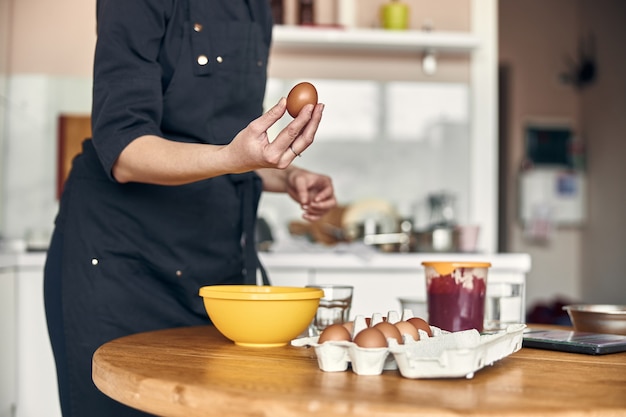 Young beautiful mixed race woman is preparing marshmallow at light modern kitchen home