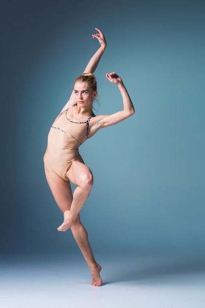 Photo young beautiful modern style dancer jumping on a studio blue background