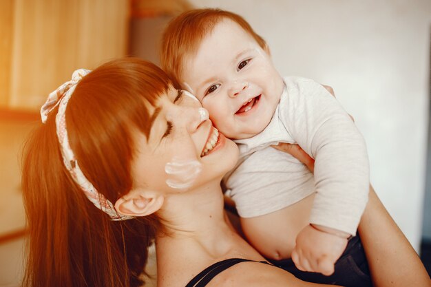 A young and beautiful mom playing with his little son at home