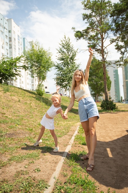 young beautiful mom with her daughter in the summer yard