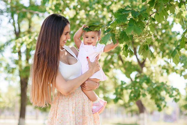 A young beautiful mother with a little daughter in the hands walking in the park.