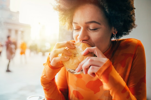 Young beautiful multiethnic woman eating hamburger