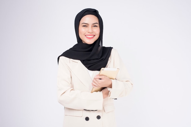 Young beautiful muslim businesswoman in suit holding tablet over white Studio background